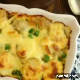 A baking dish with easy potatoes au gratin, topped with a cheesy crust and garnished with parsley, sits on a wooden table alongside a serving spoon and plates.