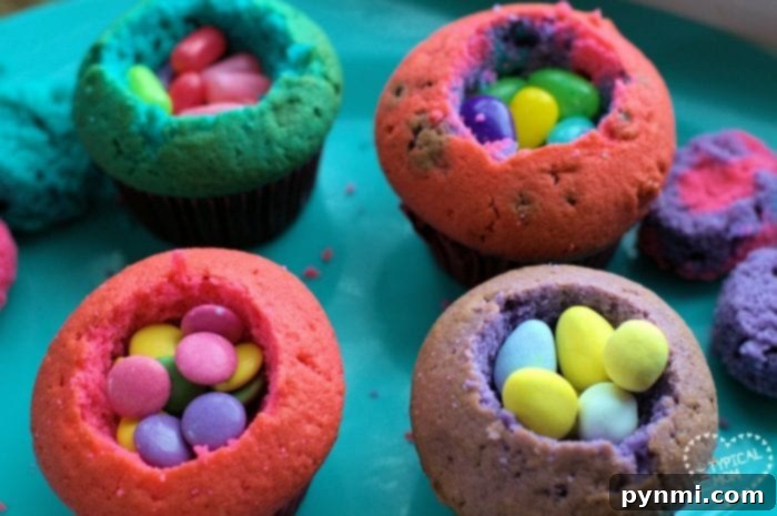 Vibrantly colored cupcakes with their wrappers removed, showcasing the consistent color throughout. They are ready to be hollowed out and filled.