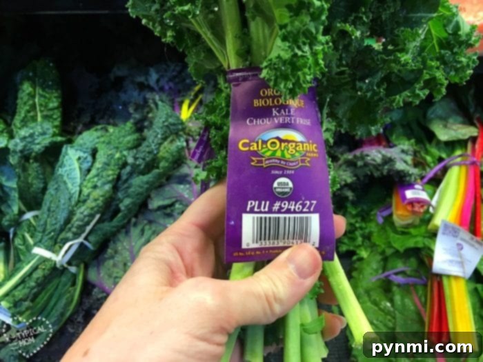 Unlock the Power of Kale: Juicing Made Easy 3 A hand holds a bunch of organic kale with a purple label in a grocery store, offering inspiration for easy kale recipes.