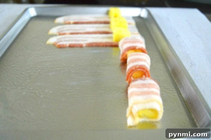Sweet and Savory Bacon Pineapple 3 Crispy, golden-brown bacon-wrapped pineapple bites, a best bacon appetizer, arranged on a white plate.