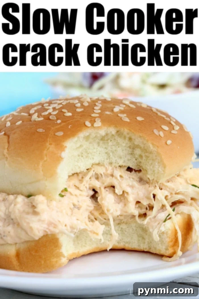 A close-up of a sesame seed bun sandwich overflowing with creamy, shredded chicken captures the eye. The text Crockpot Crack Chicken is displayed at the top of the image, enticingly highlighting its slow-cooked deliciousness.