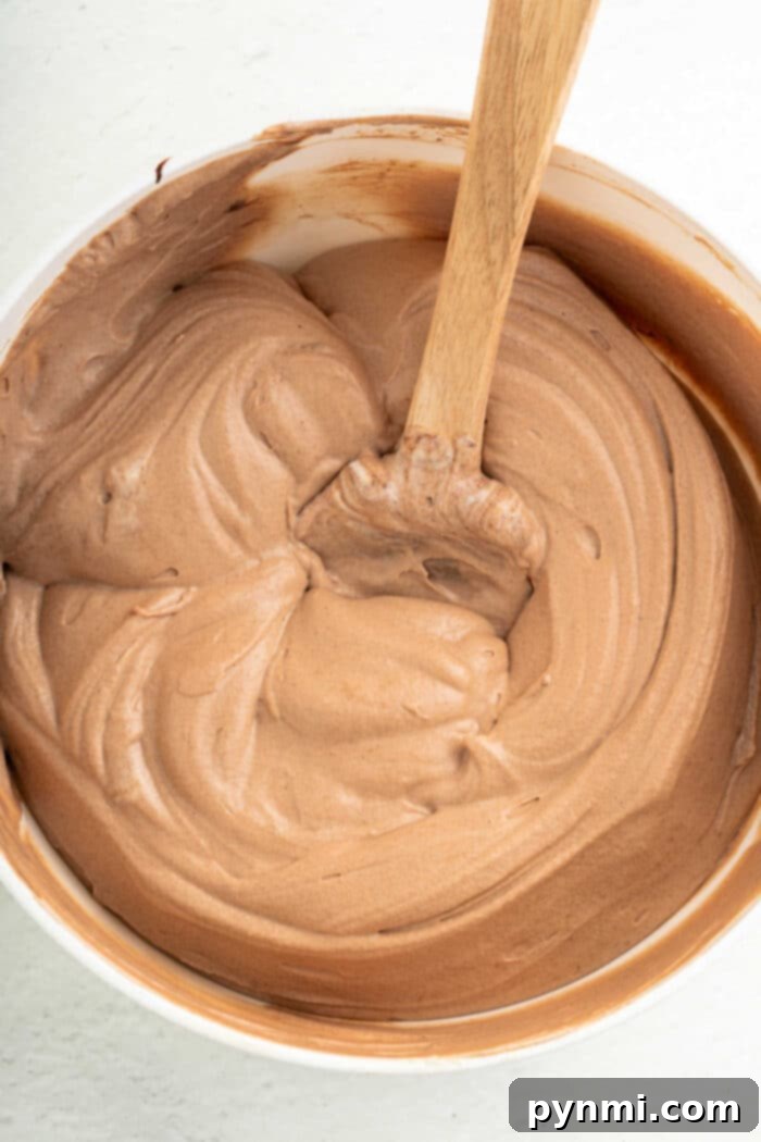Whipped Coffee Delight 5 A wooden spoon scooping creamy coffee frosting from a bowl, highlighting its smooth texture