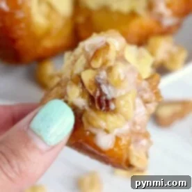 Close-up of a hand with light blue nail polish holding a piece of walnut monkey bread, perfect for brunch menu ideas.