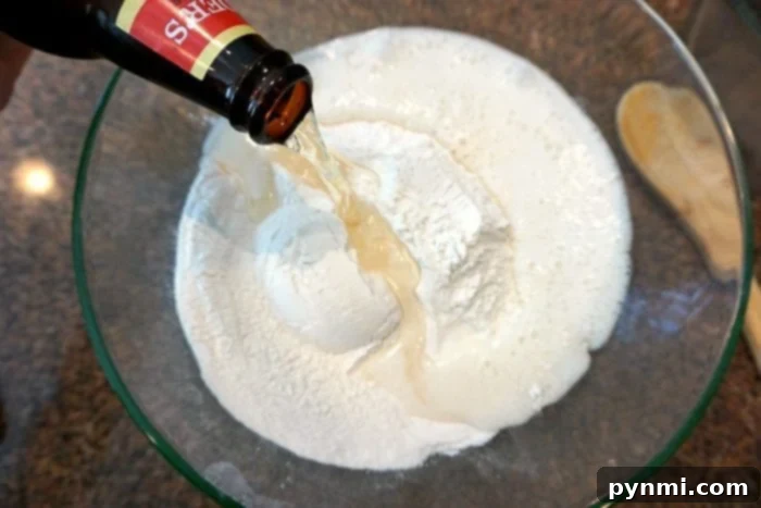 Pouring a refreshing beer into self-rising flour in a glass bowl, the initial step to crafting the best beer bread.