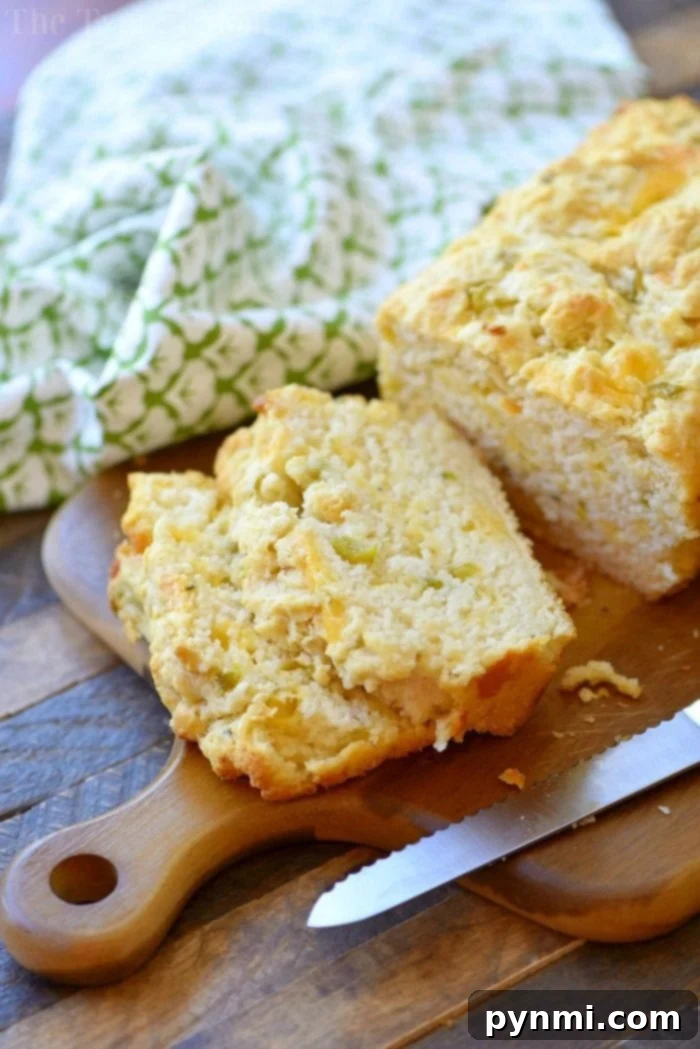 Perfectly sliced loaf of beer bread on a wooden cutting board with a knife and patterned cloth, ready to be served.
