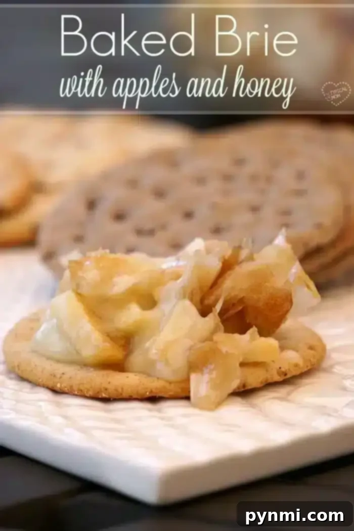 A cracker topped with easy baked Brie cheese, apple pieces, and honey sits on a white plate. Blurred crackers appear in the background. The text "Baked Brie with apples and honey" graces the top.