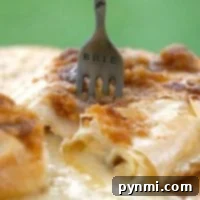 A fork labeled BRIE in melted brie cheese with a flaky phyllo dough crust rests on a wooden board.