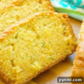 Close-up of sliced zucchini pineapple bread on a wooden surface, with a blue floral towel in the background, showing its beautiful texture.