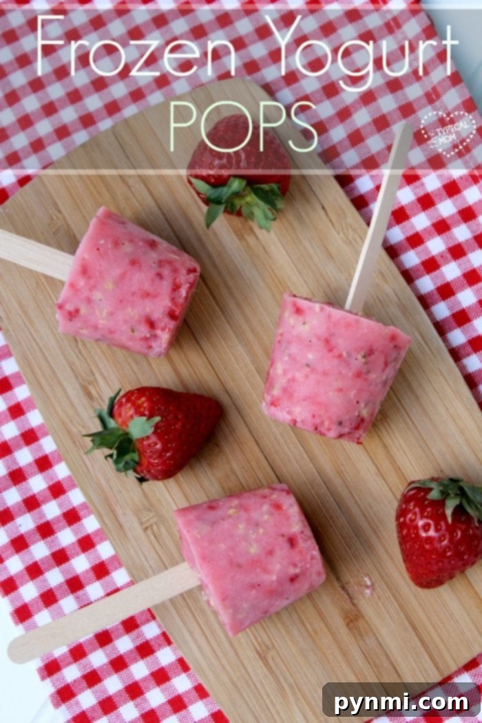 Frozen yogurt pops recipe. Two creamy frozen yogurt pops on sticks, one pink and one yellow, are nestled among a scattering of fresh berries and mint leaves, suggesting a refreshing dessert.