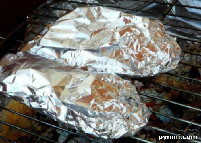 Smoky Stuffed Bell Peppers 3 Foil wrapped stuffed peppers cooking on a grill grate