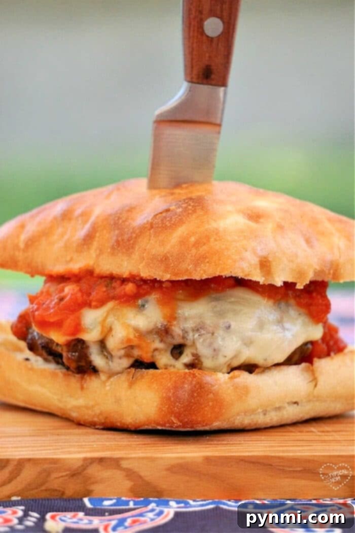 Pizzaburger Fusion 2 The New York-style burger, inspired by its pizza roots, features cheese and tomato sauce on a wooden board, elegantly topped with a knife.