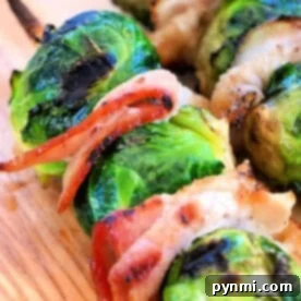 Grilled Brussels sprouts on the grill skewers with bacon rest enticingly on a wooden board.