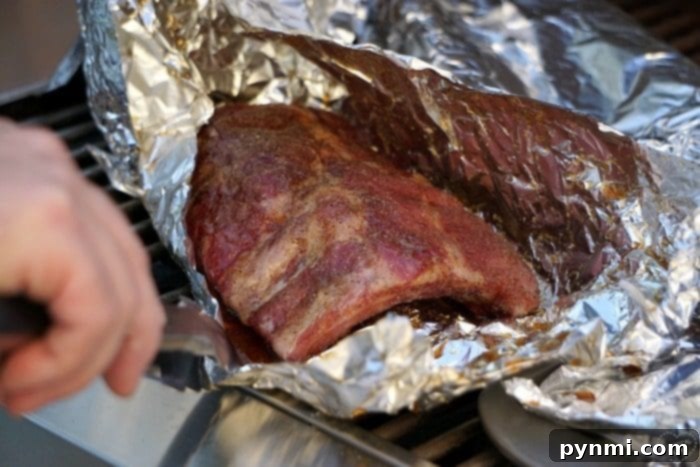 Perfectly grilled ribs wrapped in foil, ready to be unwrapped and finished for the ultimate barbecue experience. Checking the progress of our delicious barbecue ribs recipe, these grilled ribs wrapped in foil are sizzling perfectly on the grill.