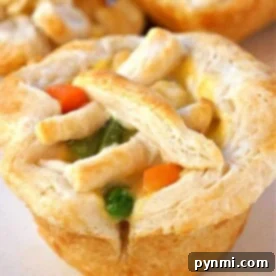 A mini chicken pot pie muffin with a flaky crust, topped with carrots, peas, and a lattice of dough strips.