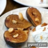 Grilled figs with nuts and a scoop of vanilla ice cream on a white plate, perfect for a fresh fig dessert