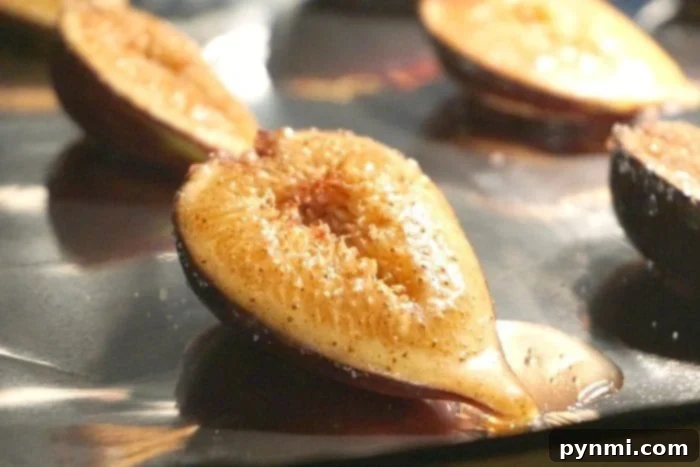 Close-up of roasted pear halves with a sprinkle of brown sugar on a baking sheet, similar to baked figs