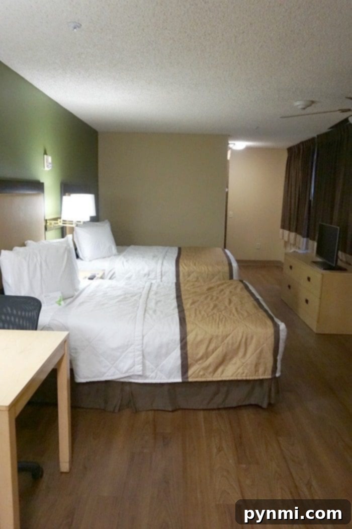 Spacious Extended Stay America hotel room with two beds and a desk area