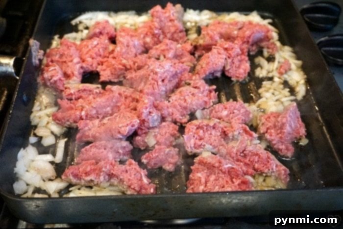 Flavorful ground beef and onions preparing for the ultimate homemade Crockpot Hamburger Helper Close-up of savory ground beef and onions browning in a pan for slow cooker recipe