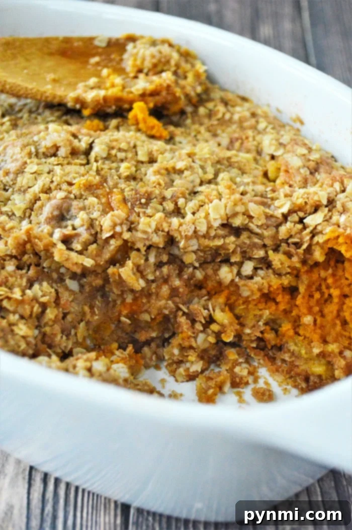 Baked sweet pumpkin crisp casserole with oat crumble topping in a white dish, reminiscent of a pumpkin crisp without cake mix.