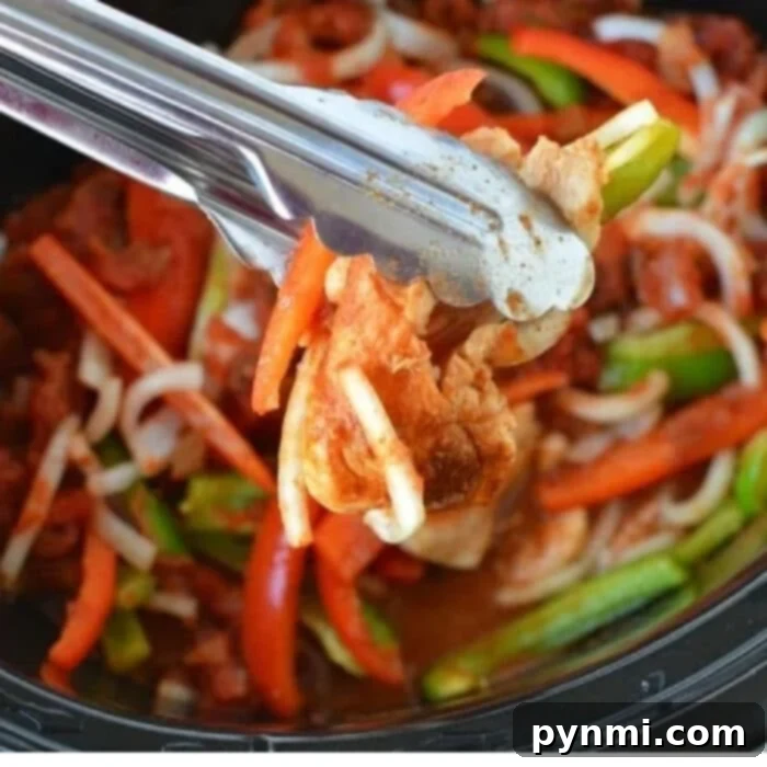 Easy Slow Cooker Chicken Fajitas 4 Close-up of shredded crockpot chicken fajitas with vibrant red and green bell peppers, cilantro, and lime wedges in a warm tortilla, highlighting the delicious texture and fresh ingredients.