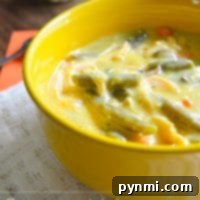 A yellow bowl of crockpot creamy chicken soup with vegetables sits elegantly on a lace tablecloth.