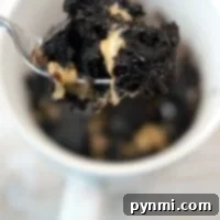 A spoonful of chocolate and peanut butter brownie being lifted from a mug offers a delightful twist on how to make a brownie in a mug.