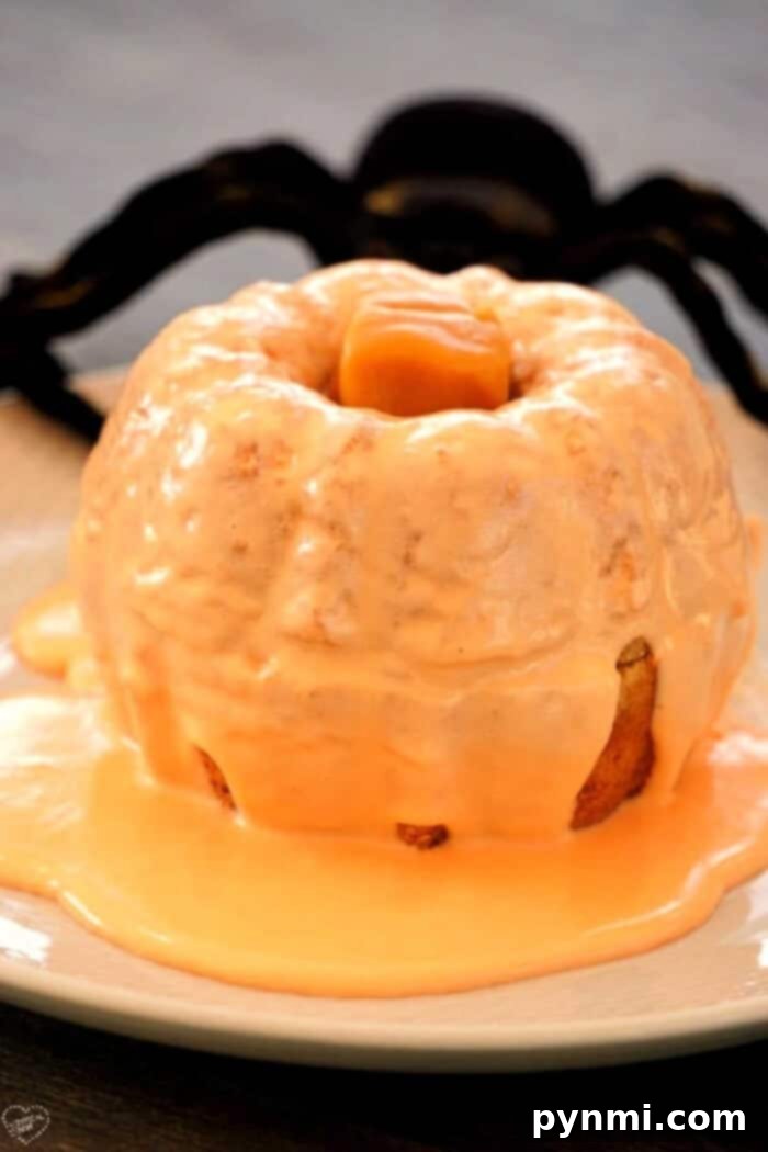 Two perfectly decorated mini pumpkin bundt cakes on a white stand, ready for a fall celebration.