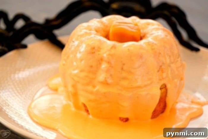 Several mini pumpkin bundt cakes adorned with orange icing and caramel stems, arranged artfully on a serving dish.