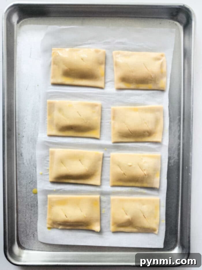 An overhead shot of homemade pumpkin turnovers with flaky crusts arranged on a white serving platter.