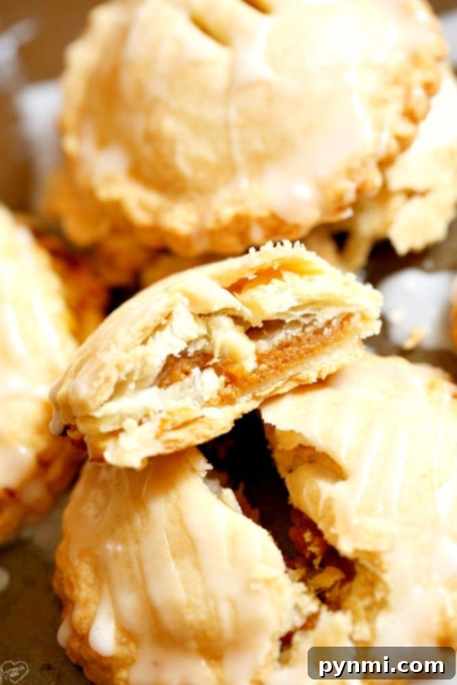 A stack of warm pumpkin pie hand pies on a rustic wooden board, ready to be enjoyed.