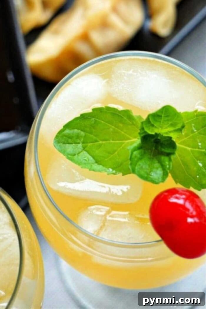 A vibrant sparkling island cocktail with a citrus twist sits on a reflective table in a stylish, blurred background setting.