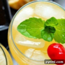 Close-up of a sparkling island cocktail with ice, a mint garnish, and a cherry on top.