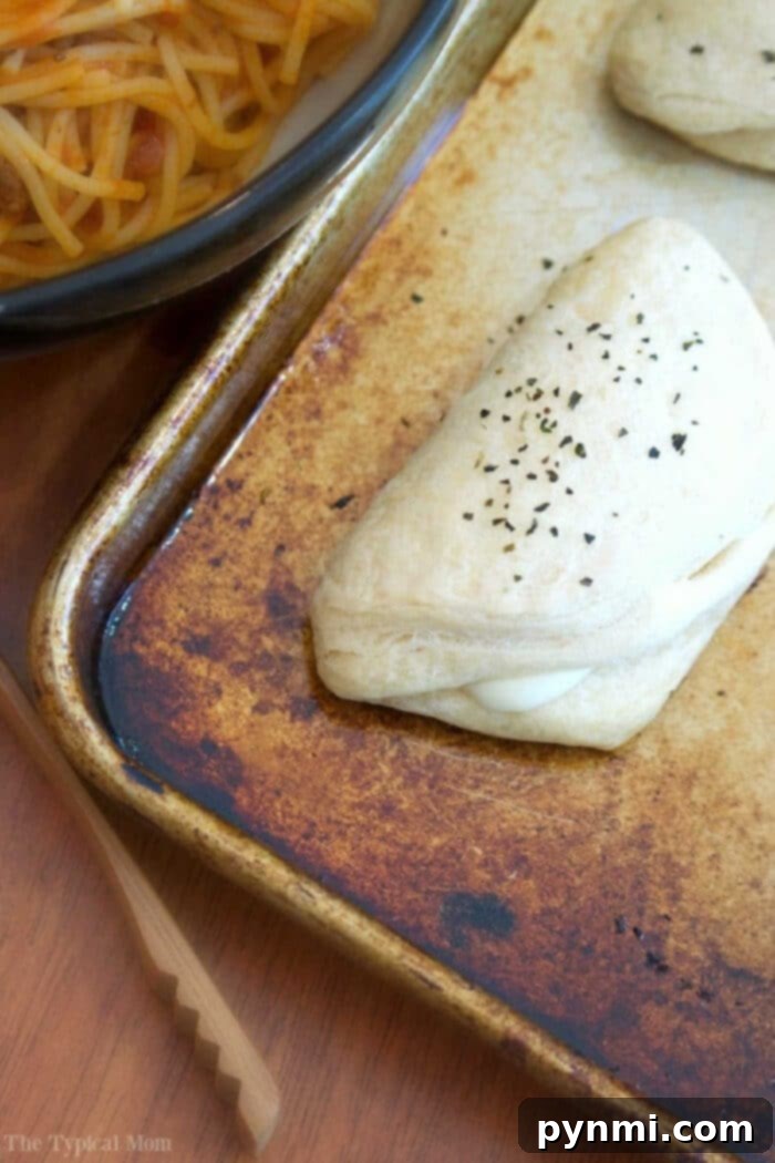Easy cheese biscuit recipe using string cheese and refrigerated biscuits. Great side dish or after school snack for kids. #rolls #biscuits Golden brown cheesy garlic biscuits arranged on a baking sheet, fresh out of the oven, with a rustic kitchen background.