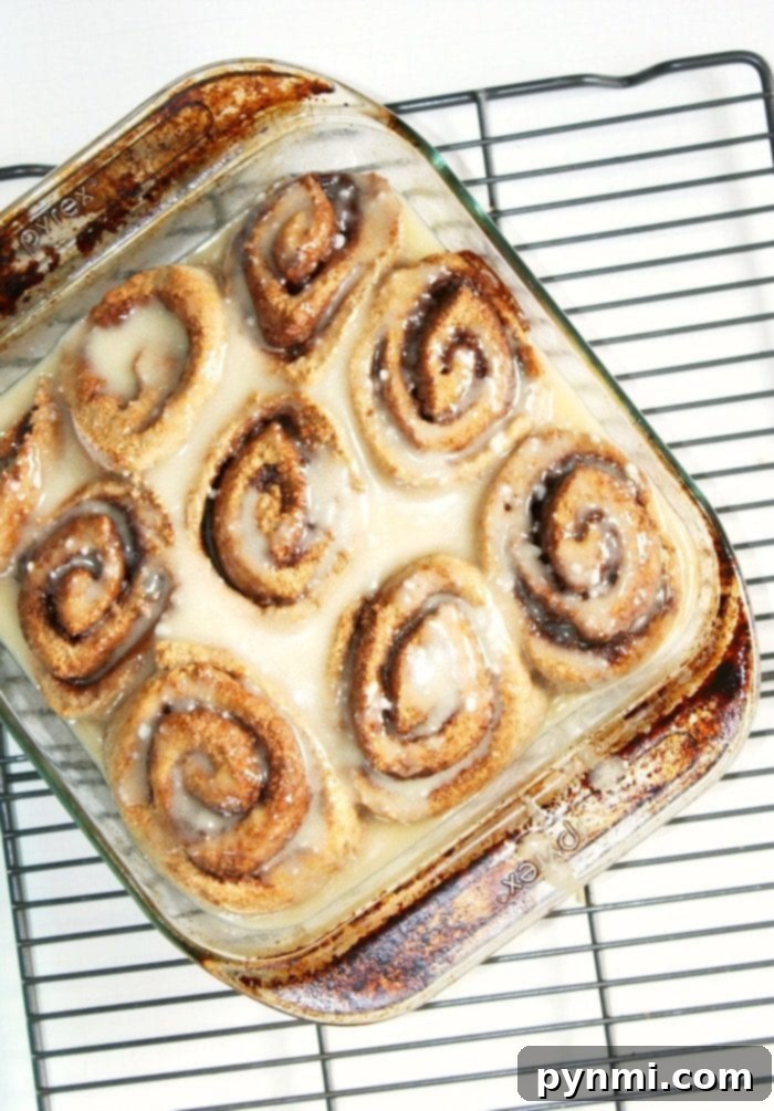 Gingerbread cinnamon rolls are amazing on Christmas morning! There's nothing like homemade cinnamon rolls and adding gingerbread is so tasty. #gingerbread #cinnamonrolls #homemade #christmas #breakfast A close-up of baked gingerbread cinnamon rolls, glistening with icing, ready for a festive celebration.
