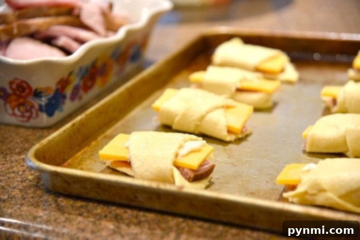 Ham and Cheese Crescent Roll-Ups 3 Close-up of ham and cheese roll-ups baking, showing some melted cheese.