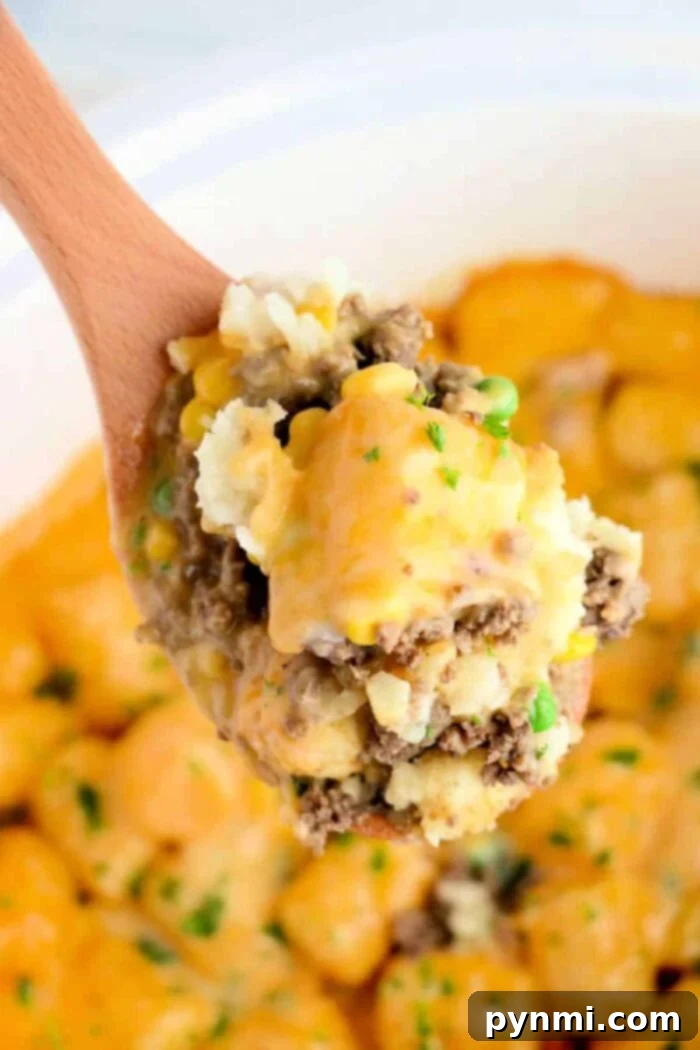 A generous serving of Crock Pot Tater Tot Casserole with a rich, creamy mushroom sauce, topped with golden melted cheese and fresh green onions for garnish.