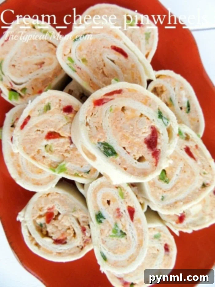 Cream cheese pinwheels are to die for!! Such an easy appetizer to serve at any occasion and packed full of flavor. A vibrant orange dish showcases a plate of cream cheese pinwheels, bursting with the colorful crunch of red and green bell peppers.