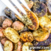 A plate of roasted potato medley, vibrant in tricolor hues and generously coated in pesto, with a fork lifting one perfect slice.