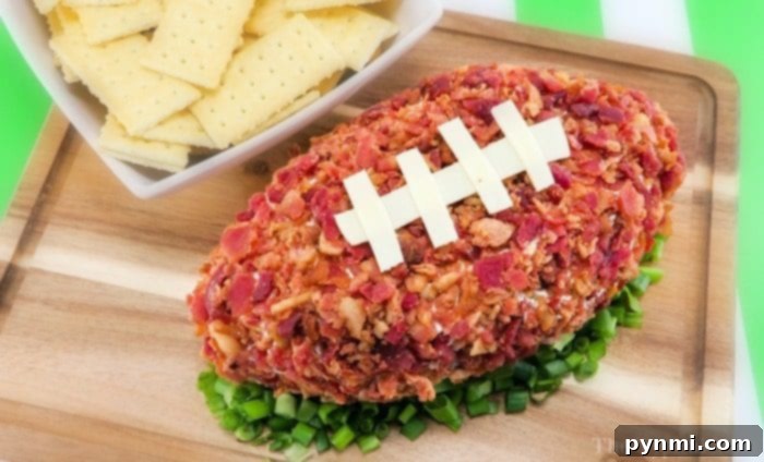 Football shaped cheese ball ever and so easy to make too. The perfect football appetizer with bacon you'll ever make and everyone will rave over at your party. Perfect Super Bowl potluck appetizer that is cheap to make and really tasty with pretzels or crackers. #football #cheeseball #cheese #appetizer #superbowl #bacon A delicious football shaped cheese ball, garnished with bacon and cheese stitching, ready to serve.