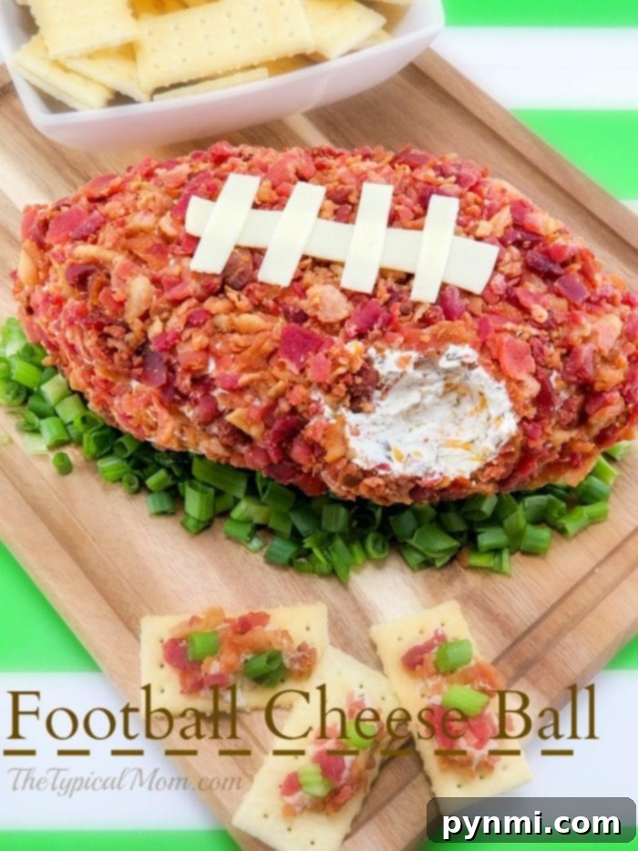 Football shaped cheese ball that's easy to make and yummy. The perfect football appetizer with bacon you'll ever make and everyone will rave over at your party. Perfect Super Bowl potluck appetizer that is cheap to make and really tasty with pretzels or crackers. #superbowlappetizer #football #cheeseball #cheese #appetizer #superbowl #bacon Large, appetizing football shaped cheese ball on a serving platter surrounded by crackers and fresh green onions.