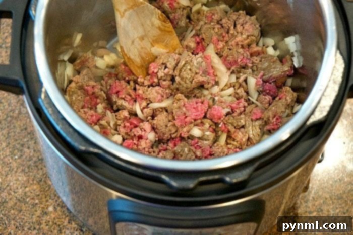 Instant Pot lasagna soup is amazing and healthy!! You can make it in the slow cooker too but in your pressure cooker it's done in just 8 minutes! #lasagnasoup #lasagna #soup #instantpot #pressurecooker #instantpotrecipes #thetypicalmom Ground beef and chopped onions cooking in an Instant Pot for lasagna soup