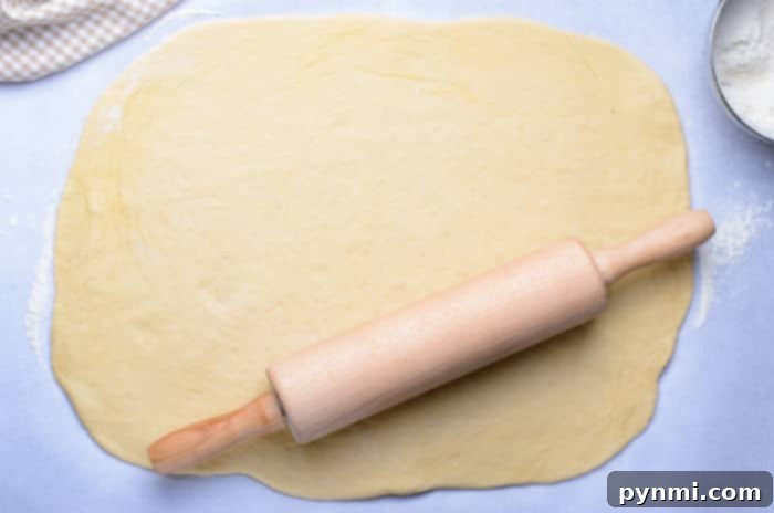 Crafting Edible Gems: Stained Glass Cookies 3 Cookie dough being rolled out on parchment paper with a rolling pin.