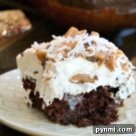 Indulge in a slice of Chocolate Coconut Poke Cake, lavishly adorned with whipped cream, toffee bits, and coconut on a pristine white plate.