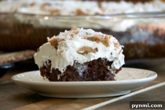 A close-up view of the rich, moist interior of a caramel poke cake, showing the caramel soaking into the chocolate cake layers, topped with whipped cream and crushed toffee, ready to be served.