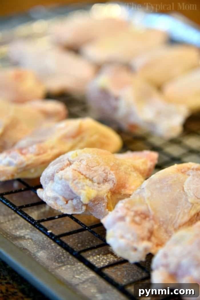 Close-up of golden-brown Sriracha Chicken Wings on a baking rack, glistening with sweet and spicy sauce.