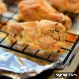 Close-up of irresistible, crispy chicken wings baked to perfection on a cooling rack with foil underneath