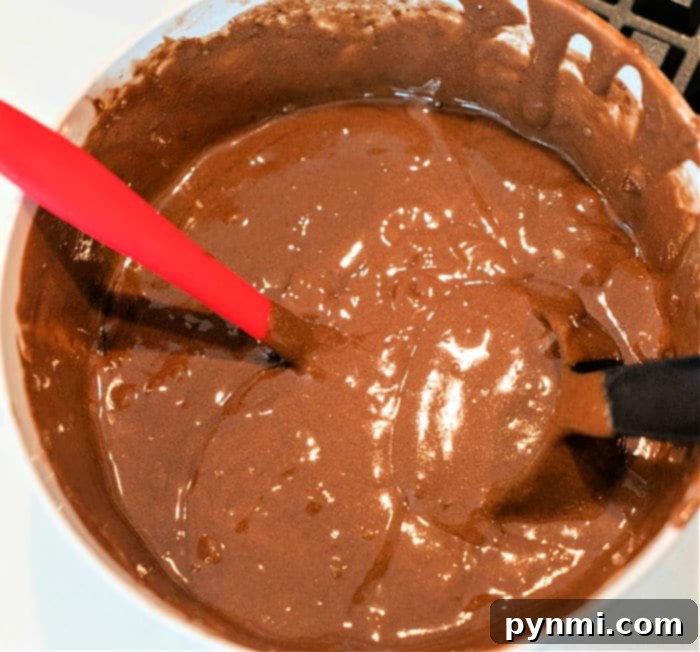Cake batter being poured into waffle bowls on a baking sheet, showcasing the preparation for baking delicious edible cupcake bowls.