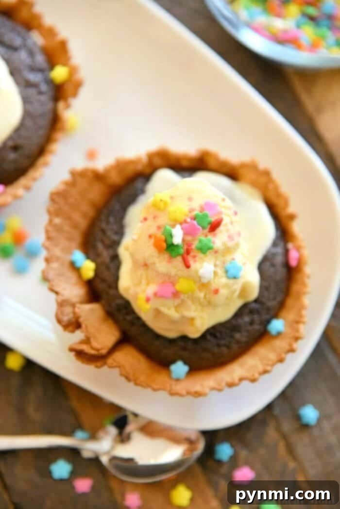 A festive array of Sundae Cupcakes with ice cream, whipped cream, sprinkles, and cherries in edible waffle bowls, ready for a party.