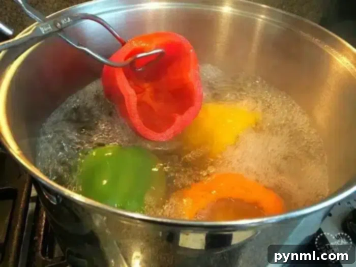 A stainless steel pot filled with boiling water on a stove holds green, yellow, and orange bell peppers. A metal utensil expertly demonstrates how to blanch bell peppers by submerging a red one into the water.