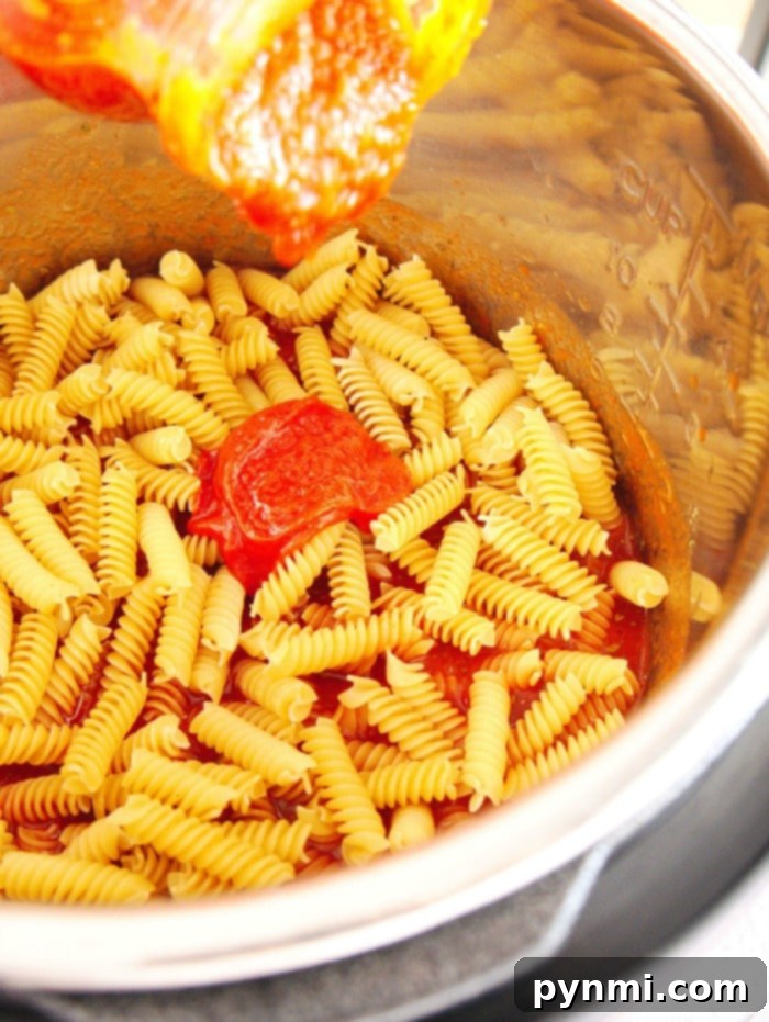 Pressure cooker pizza pasta is great! Super easy to dump it all in your pressure cooker and put in all of your favorite pizza toppings. #instantpotpizzapasta #instantpot #pizza #pasta #dinner #instantpotrecipes #thetypicalmom #pizzapasta A vibrant bowl of Instant Pot pizza pasta, showcasing colorful toppings like pepperoni, olives, and fresh herbs, ready to be enjoyed.